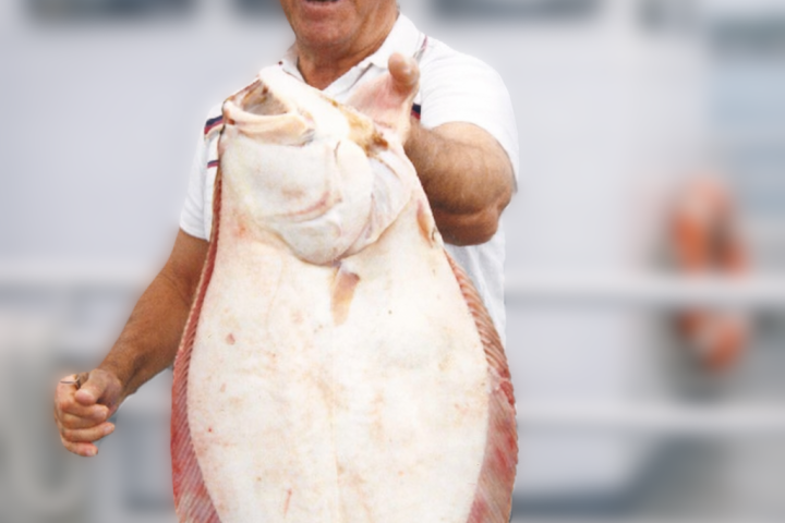 Man holding a large fish on a boat with blurred background.